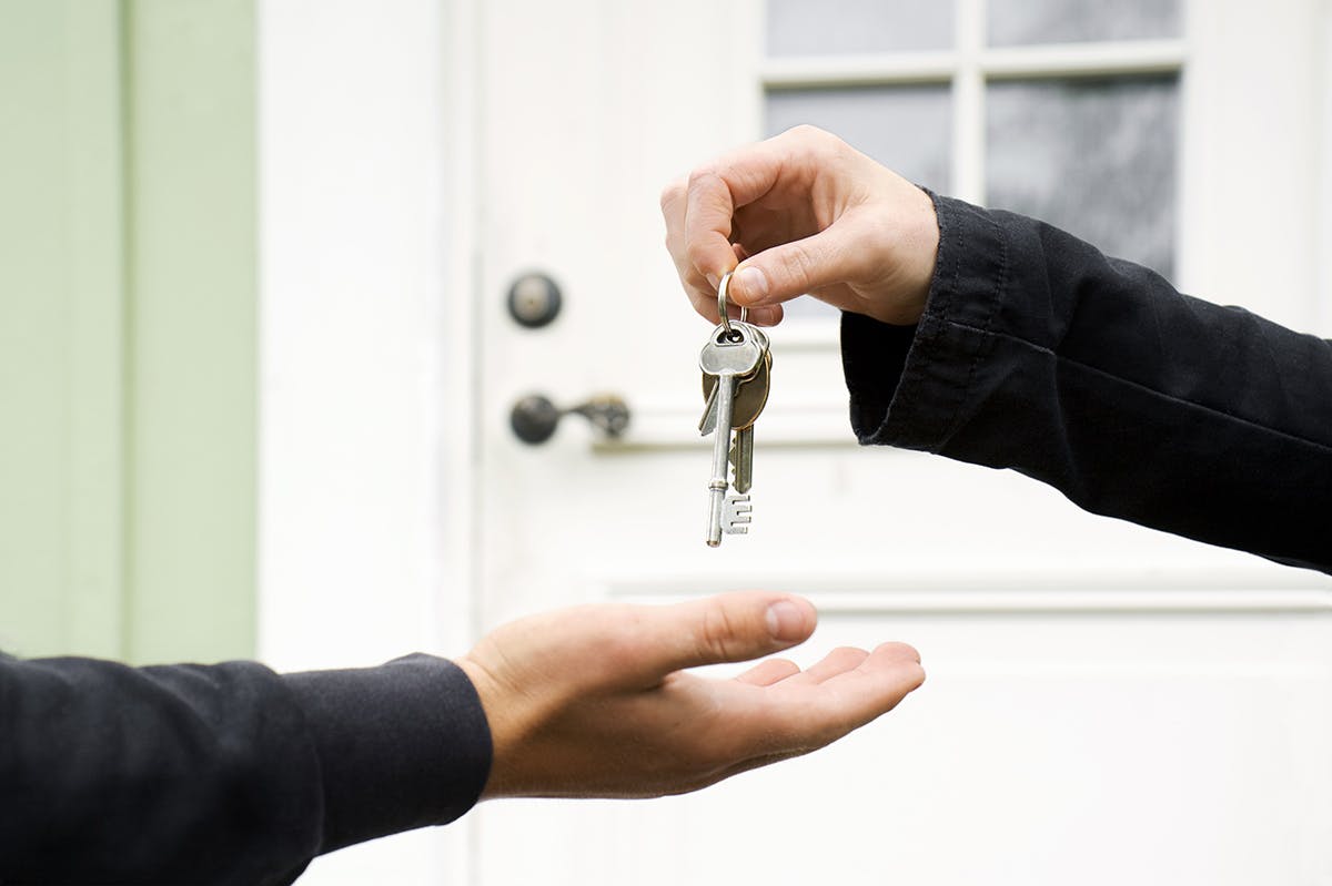 a person handing over house keys to another person